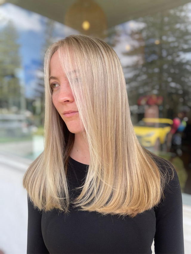Golden blonde blow wave with a glossy, straight finish