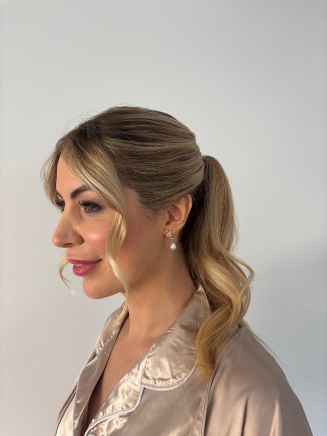 Blonde event ponytail with soft face-framing tendrils