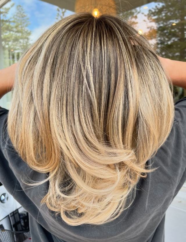 Blonde highlighted mid-length cut with soft layers, back view